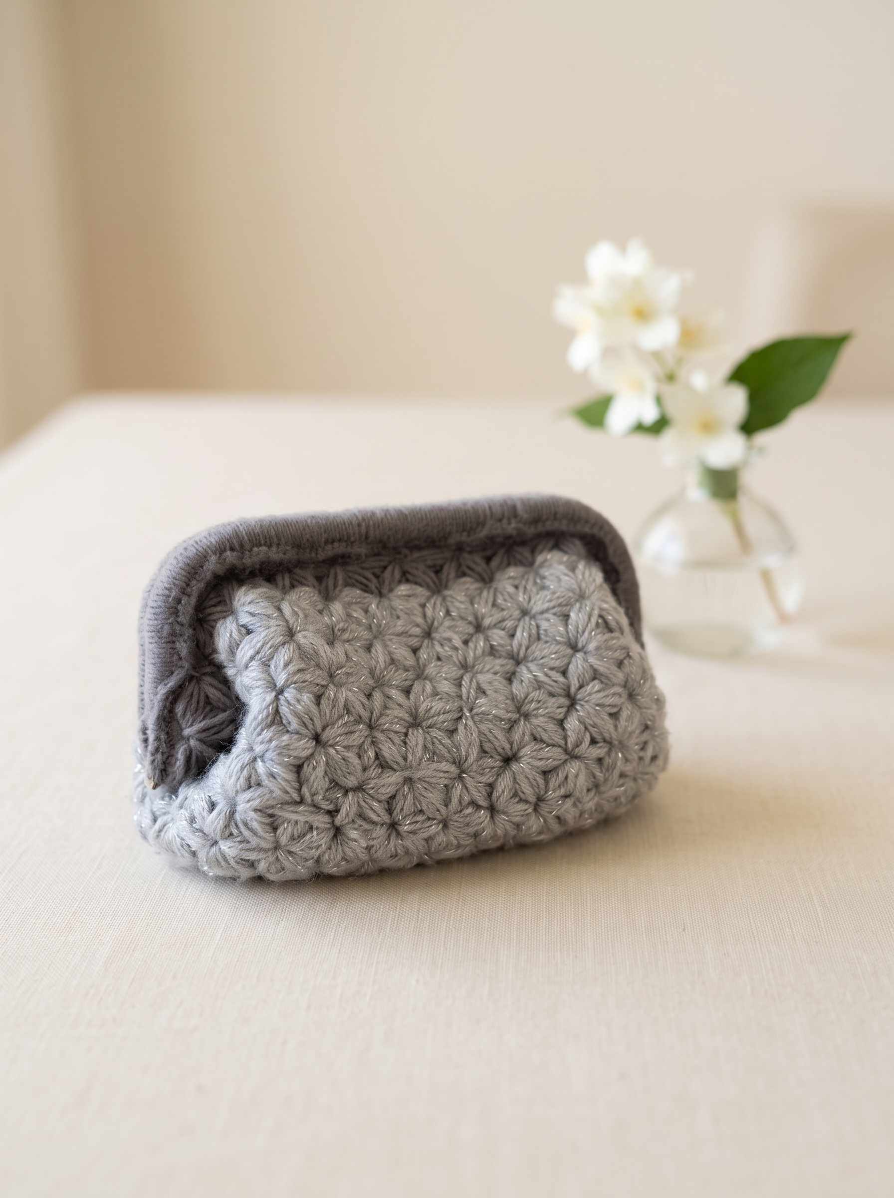 Grå heklet clutch med jasminmønster og jasminblomster i vase